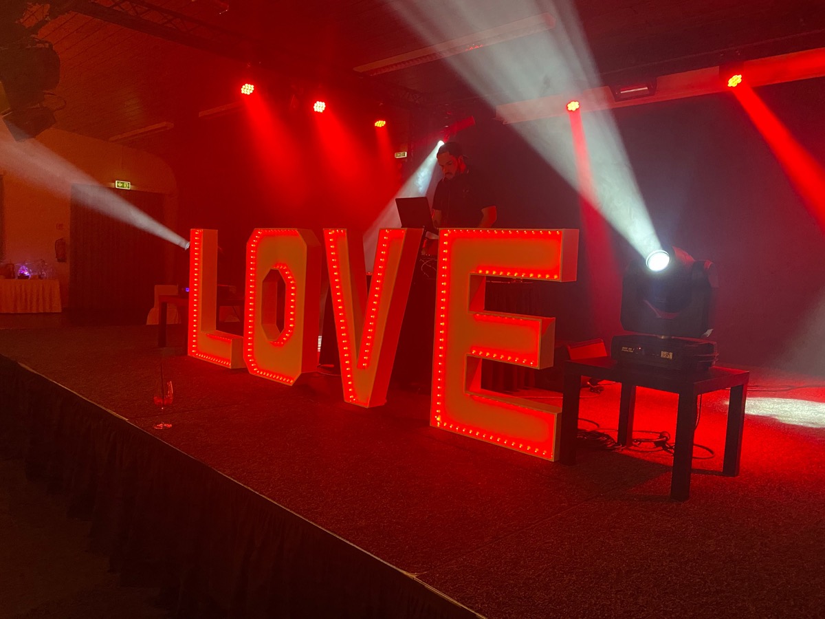 DJ-Pult hinter rot leuchtenden LOVE-Buchstaben auf einer Hochzeit